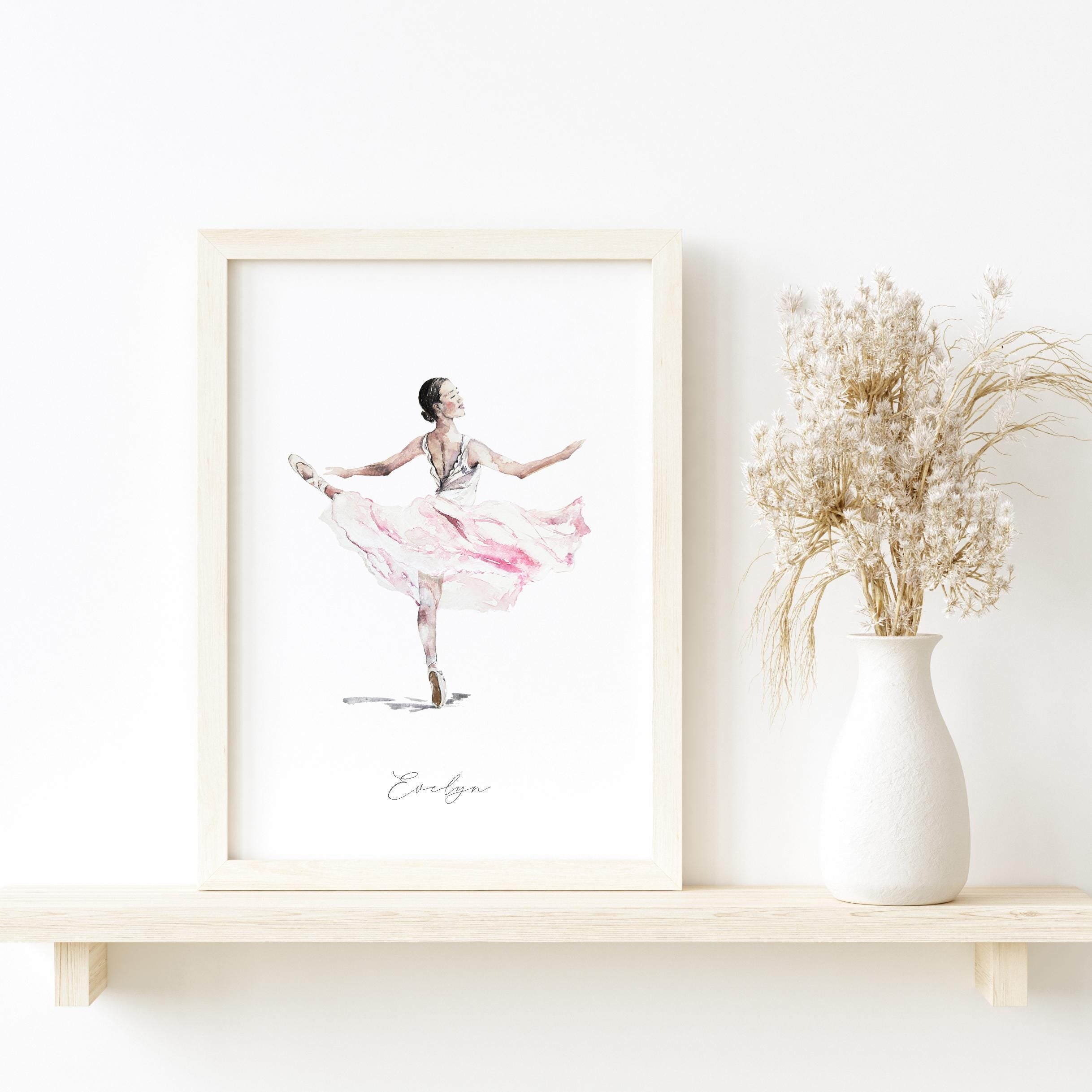 Framed artwork of a ballerina in a pink dress on a shelf with a vase of dried flowers.