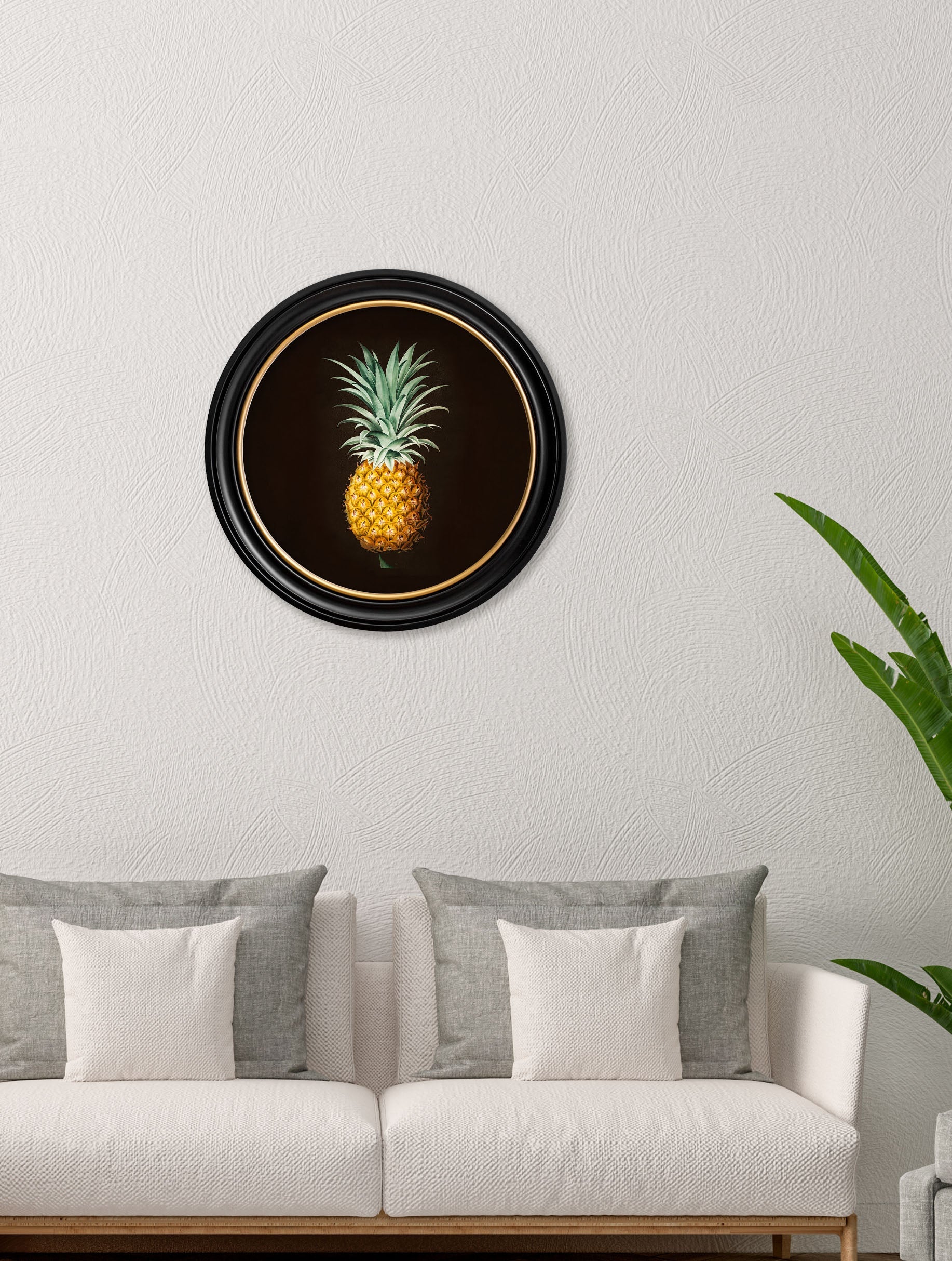 Framed artwork of a pineapple on a wall above a sofa.