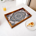 Decorative mosaic tray on a table with a slice of pie and a glass of orange juice.